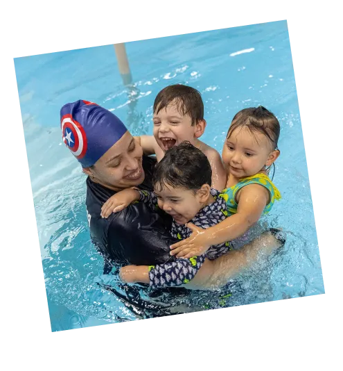 Professora de natação com touca do Capitão América na piscina com 3 crianças no color